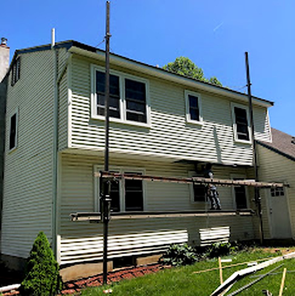 Vinyl siding installation in progress with scaffolding on home