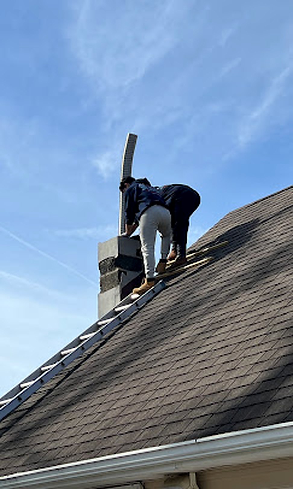 Worker climbing roof carrying chimney flashing material