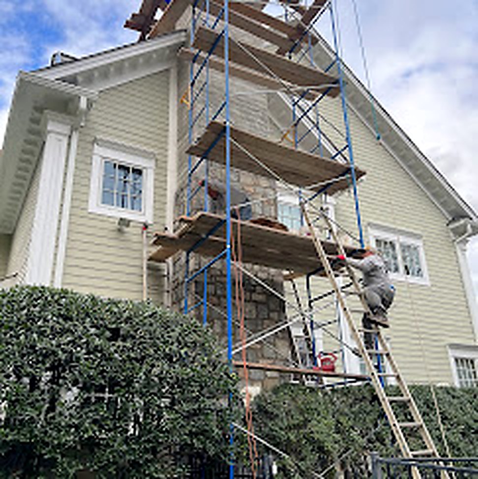 Yellow Victorian home with full scaffolding during siding installation